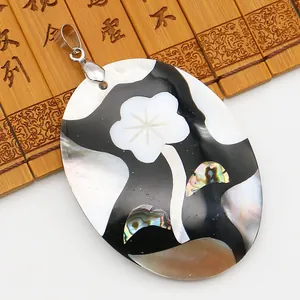 Détail macro du pendentif ovale en nacre fait main avec motif floral sur bambou