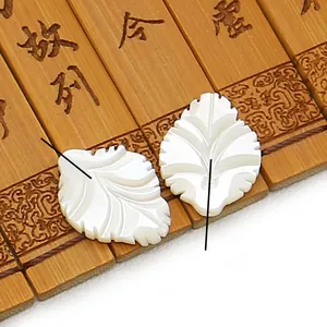 Détail de perles de nacre blanche sculptées en forme de feuille pour bijoux sur bambou
