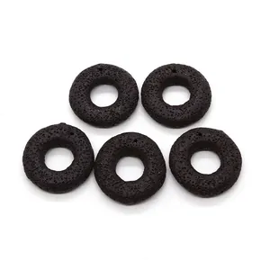 Macro detail of five black lava stone donut pendants with natural porous texture for DIY