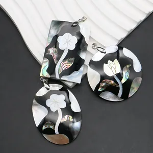 Pendentifs faits main en nacre et abalone avec motifs floraux sur fond sombre moderne