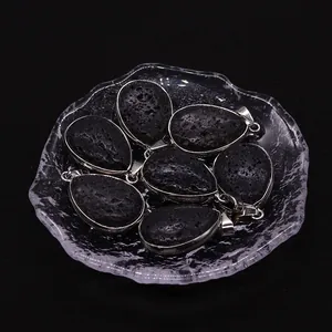 Natural black lava rock teardrop pendants with silver metal bezel in a glass dish