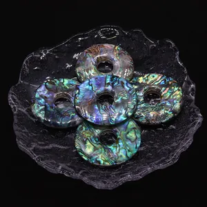 Cinq pendentifs en nacre d'abalone naturelle aux reflets irisés sur plateau