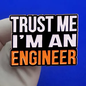 Αστεία καρφίτσα 'Trust Me I'm An Engineer' με μαύρο φόντο και πορτοκαλί γράμματα