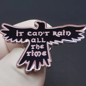 Enamel black bird brooch with 'It Can't Rain All The Time' text and purple metallic edges