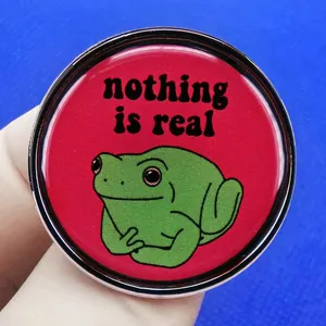 Cartoon frog enamel pin with nothing is real text on vibrant red background