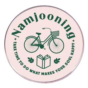 Namjooning-Anstecker in Rosa mit grünem Fahrrad und Buch auf weißem Hintergrund