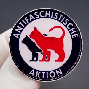 Antifascist Action enamel pin with red and black cat silhouettes on round metal badge