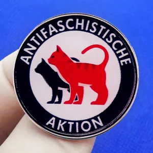 Antifascist action round enamel pin with red and black cats on a vibrant blue background