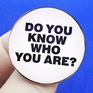 Runder Emaille-Pin mit weißem Hintergrund und schwarzem Do You Know Who You Are? Text