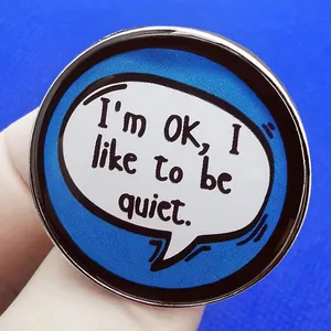 Enamel pin featuring 'I'm OK, I like to be quiet' slogan on dark blue round metal badge