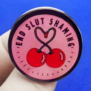 Broche en émail rose avec cœur cerise et slogan End Slut Shaming sur fond bleu