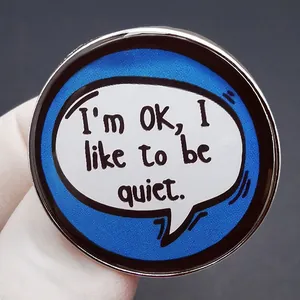 Round metal brooch with blue mesh pattern and I'm OK I like to be quiet slogan