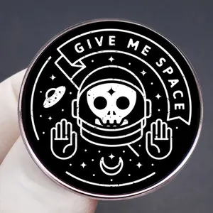 Give Me Space enamel pin featuring astronaut skull and celestial elements on a black badge