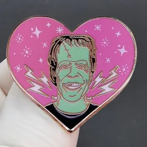 Heart-shaped Frankenstein enamel pin with green cartoon character on pink background
