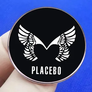 Schwarze Placebo Band Emaille Pin mit weißen Flügeln auf blauem Stoffhintergrund