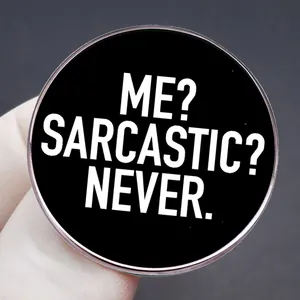 Pin's rond en métal noir 'ME? SARCASTIC? NEVER.' avec bordure argentée élégante