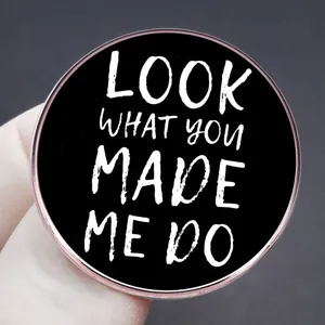 Black round Taylor brooch with Look What You Made Me Do text and rose gold trim