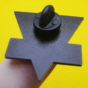 Vue arrière du pin's INGSOC en émail noir avec fermoir en caoutchouc sur fond jaune