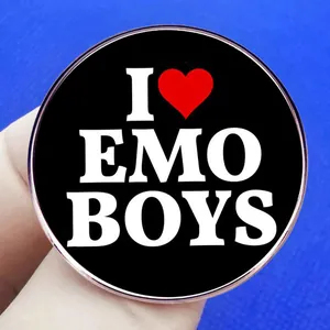 Black round emo boys metal badge with red heart symbol held in gloved hand