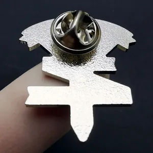 Achterkant van de zilveren metalen S-logo speld met matte textuur en vlindersluiting