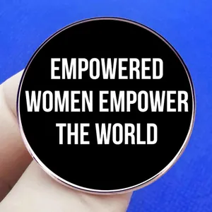 Feminist enamel brooch pin with Empowered Women Empower The World quote on blue fabric
