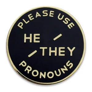 Pin de esmalte negro con texto dorado que dice Please Use He They Pronouns