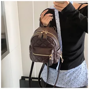 Detail of dark brown quilted mini backpack with gold zippers and polished leather texture