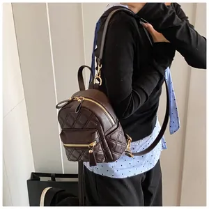 Detail view of dark brown quilted mini backpack with golden zippers and adjustable straps