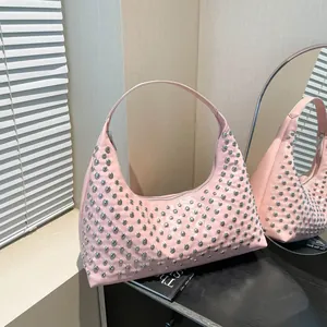 Sac hobo rose brillant avec clous argentés posé sur un support d'exposition