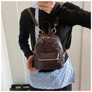 Detail of dark coffee quilted leather mini backpack with golden zipper and metal hardware