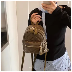 Detail of dark green quilted leather mini backpack with golden zippers and long pullers