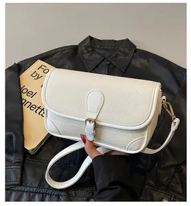 Détail de la texture en cuir litchi blanc d'un sac bandoulière carré avec boucle