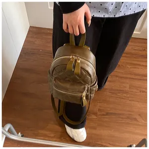 Close-up of olive green quilted mini backpack featuring shiny leather and gold hardware