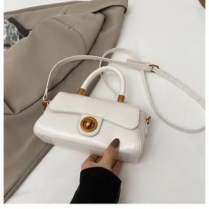 Détail du sac bandoulière blanc crème avec fermoir doré et texture cuir mat raffinée