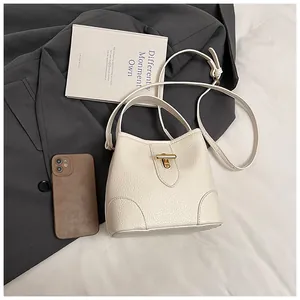 Detailed close-up of cream textured leather bucket bag with gold lock and shoulder strap