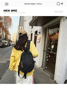 Rear view of model wearing a black washed denim backpack in an urban setting