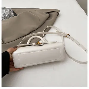 Détail du sac à main crème montrant les coutures précises et le fermoir rotatif doré