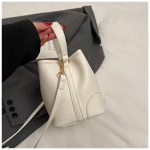 Close-up of white bucket bag featuring pebble leather texture and gold-tone metal hardware