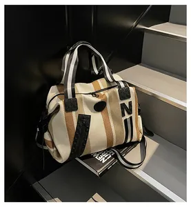 Close-up of striped canvas tote bag with leather corners and branded 'N' detail