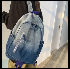 Détail du sac à dos en jean dégradé avec sangles violettes et tirette de zip à franges