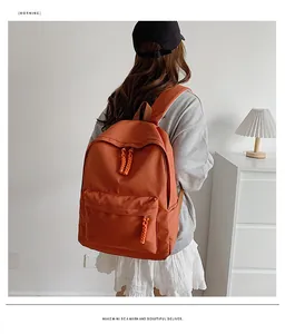 Detail of an orange canvas backpack featuring a woven rope zipper and front storage pocket