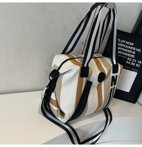 Detail of striped canvas tote bag showing top zipper closure and adjustable shoulder strap