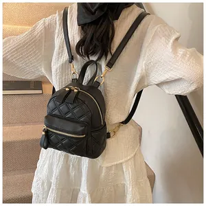 Close-up of a black quilted mini backpack with gold zippers and a front zip pocket