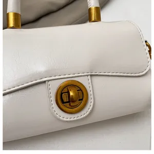 Gros plan sur un sac en cuir crème avec fermeture à fermoir doré vintage