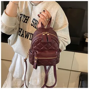 Close-up of the wine red quilted leather texture and gold metal zipper on the mini backpack