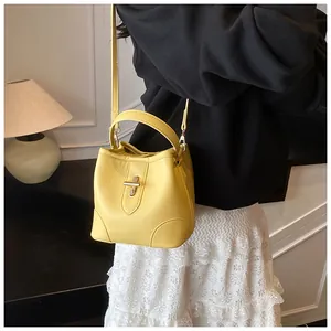 Detail of yellow bucket bag with lychee grain leather and golden metal twist lock closure