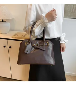 Détail du sac cabas en cuir brillant marron foncé avec ferrures dorées et étiquette