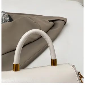 Détail du sac à main blanc avec poignée ronde et quincaillerie métallique dorée cylindrique
