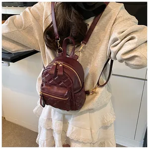 Model wearing a burgundy quilted mini backpack in soft matte PU leather with gold zippers