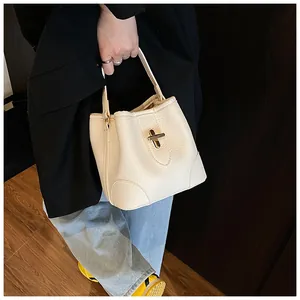 Detail of minimalist cream-white bucket bag with lychee grain leather texture and gold hardware